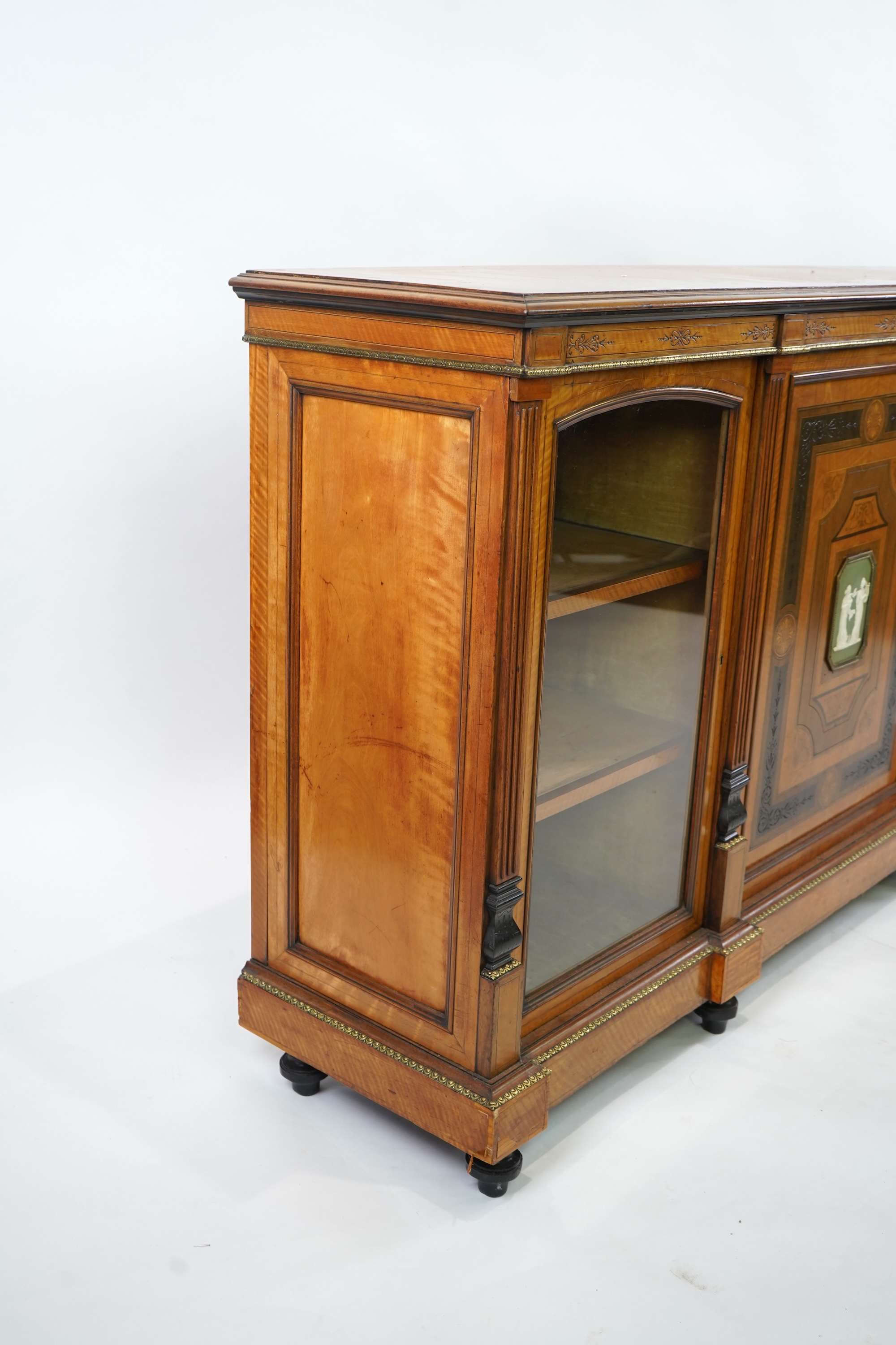 A Victorian marquetry inlaid and gilt metal mounted banded satinwood side cabinet, with anthemion carved frieze over a central door applied octagonal Wedgwood style green and white octagonal jasper plaque, flanked by gla